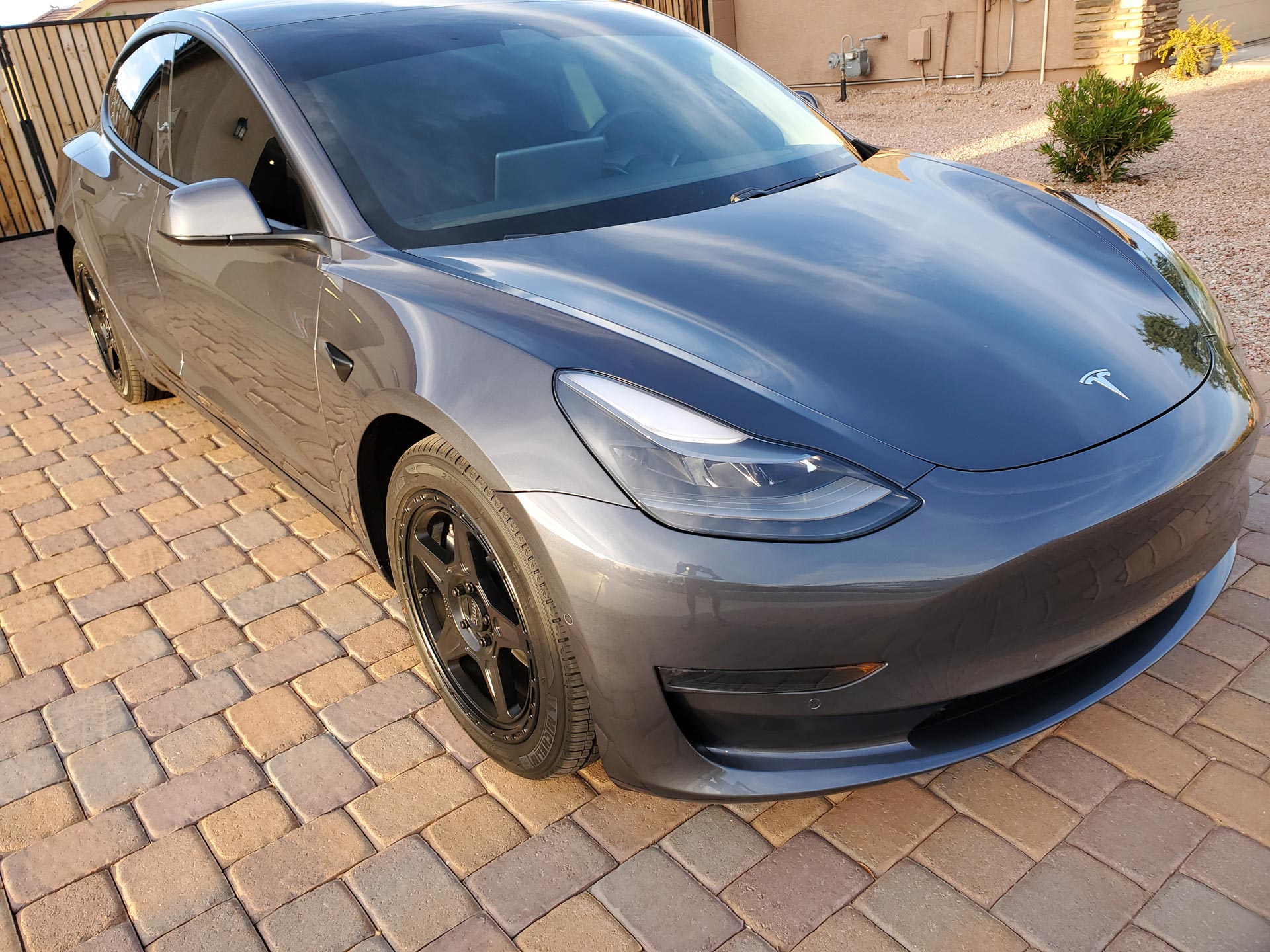 A Tesla Model 3 Parked on a Brick Driveway